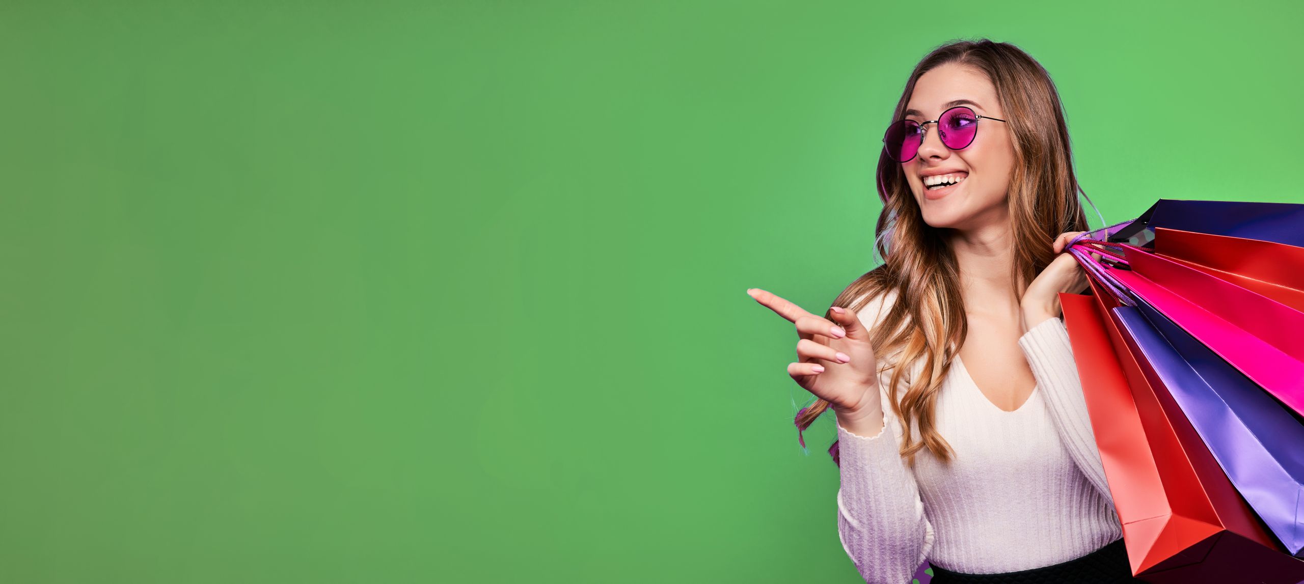 Beautiful smiling young blonde girl pointing in sunglasses holdi